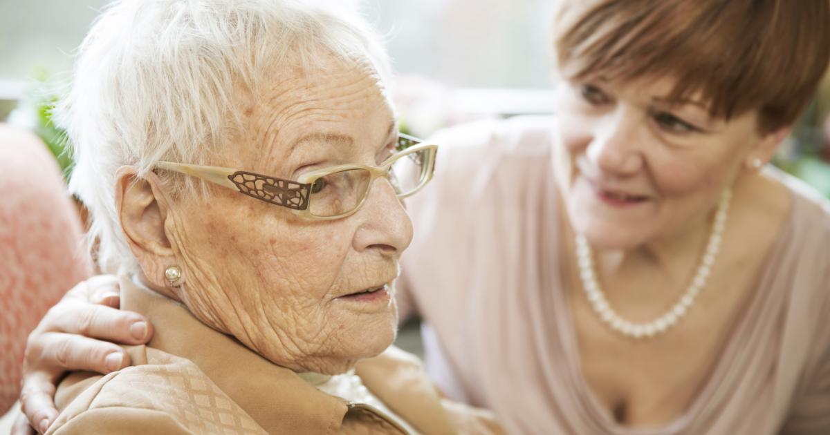 Una mujer charla con una paciente de Alzheimer.