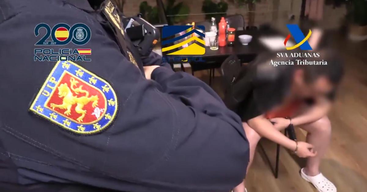 Uno de los agentes custodia a uno de los detenidos durante uno de los registros practicado.