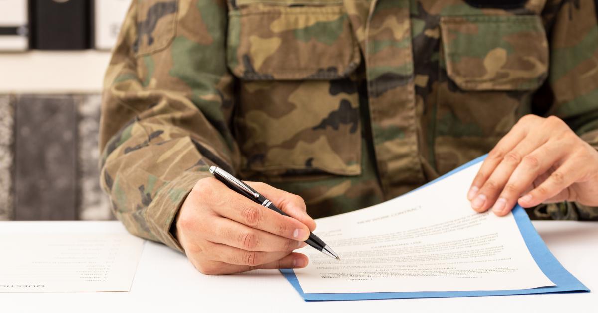 Un militar firma un contrato.