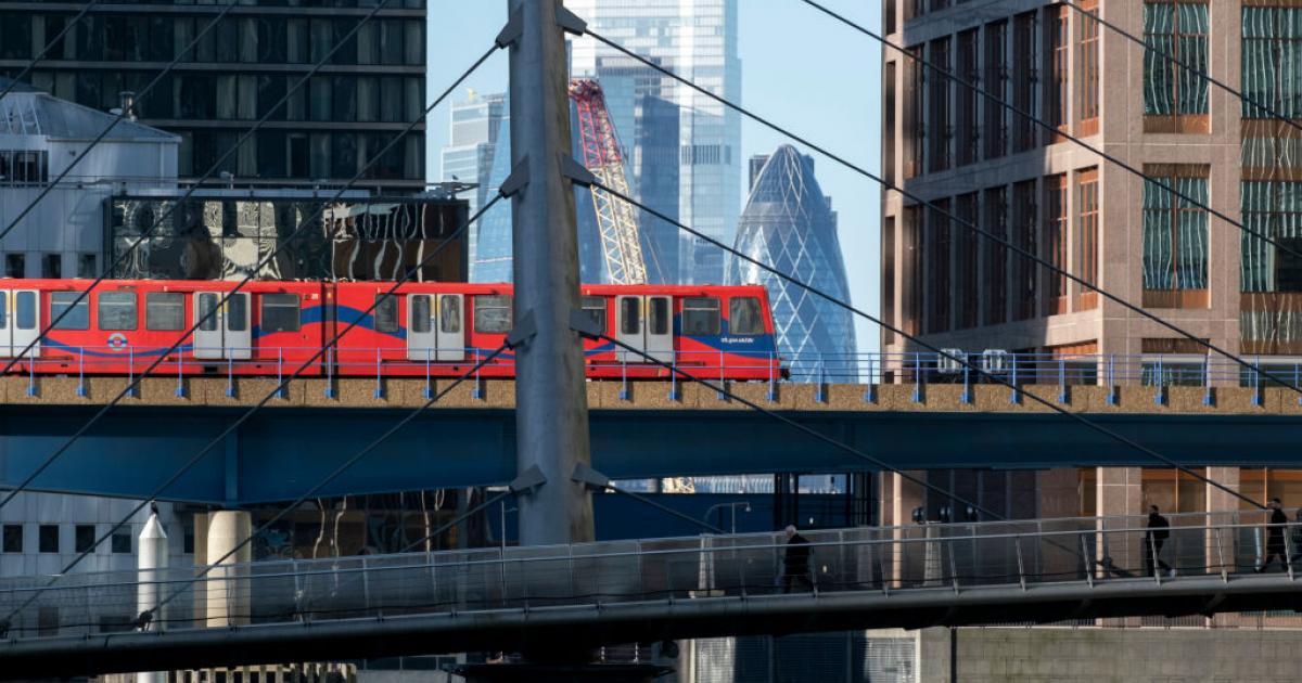 Uno de los trenes de la red DLR de Londres con los rascacielos de la City de fondo.