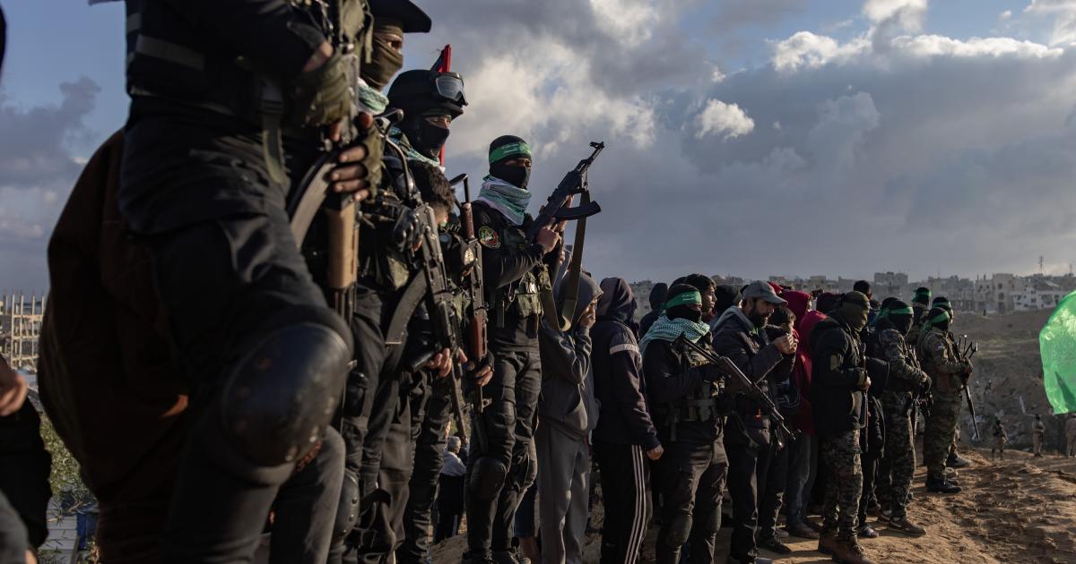 Combatientes de Izz ad-Din al-Qassam siguen la entrega de los cuerpos de cuatro rehenes israelíes a la Cruz Roja, en Khan Yunis, sur de la Franja de Gaza, este jueves.