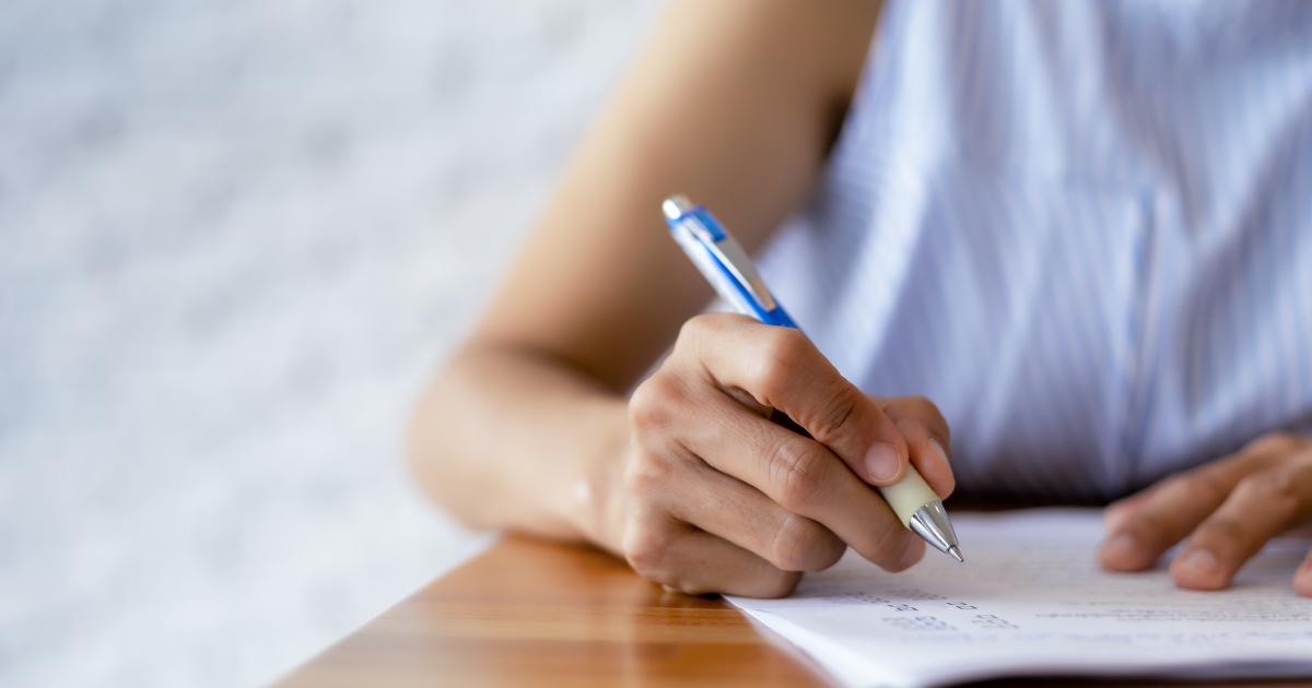 Imagen de una persona escribiendo en un papel.