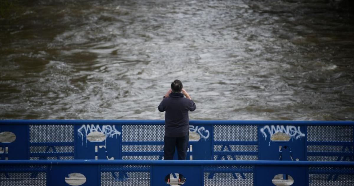 Una persona fotografía el curso del río de Manzanares, crecido por las intensas lluvia que trae la borrasca Martinho.