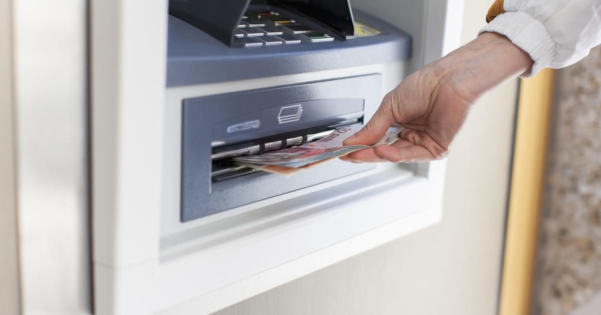 Una persona sacando dinero en un cajero automático, en una imagen de archivo.