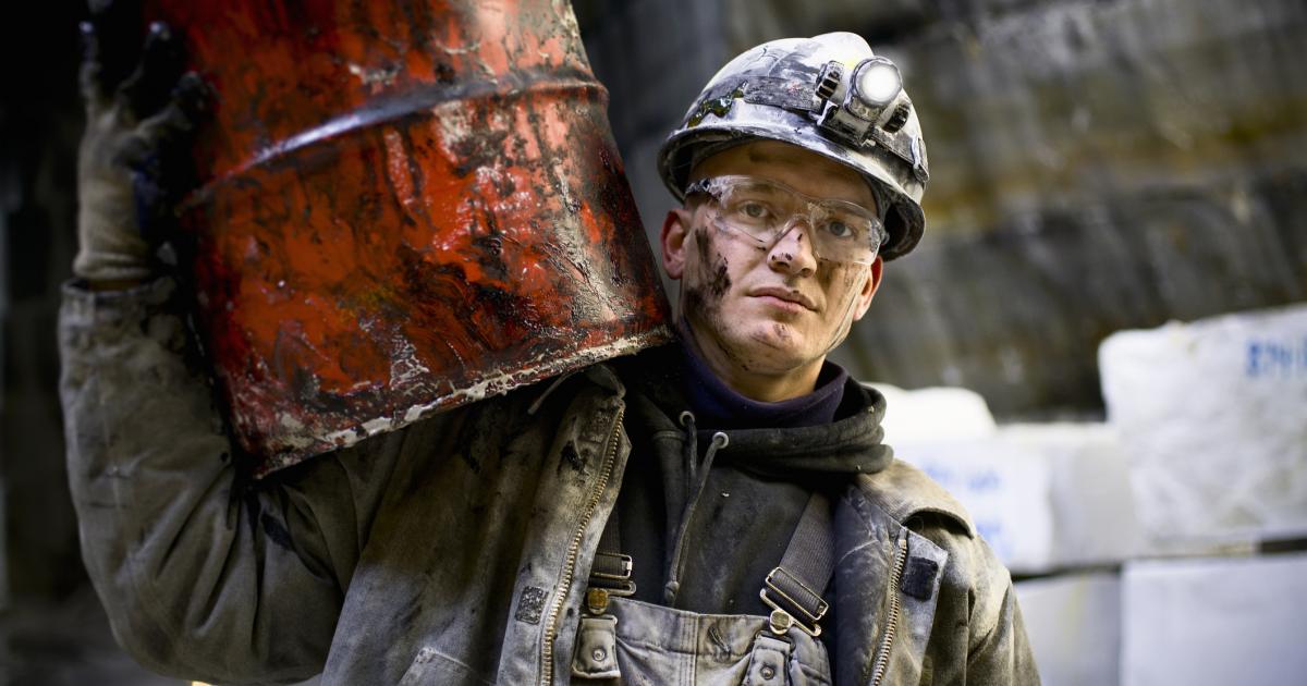 Imagen de un hombre cargando con un barril de petróleo.