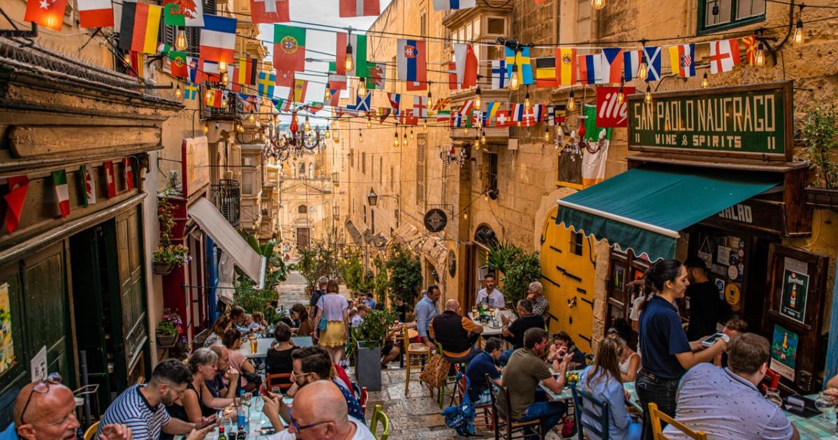Un grupo de turistas come en un restaurante abierto en uno de los callejones de la capital de Malta, La Valeta.