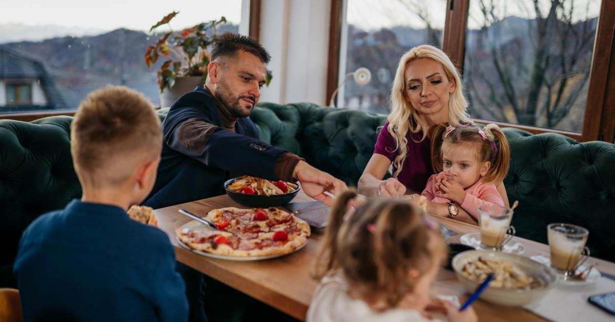 Padres comiendo en un restaurante con sus hijos.