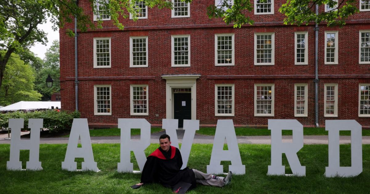 Un estudiante de Harvard posa ante un cartel de la universidad estadounidense.