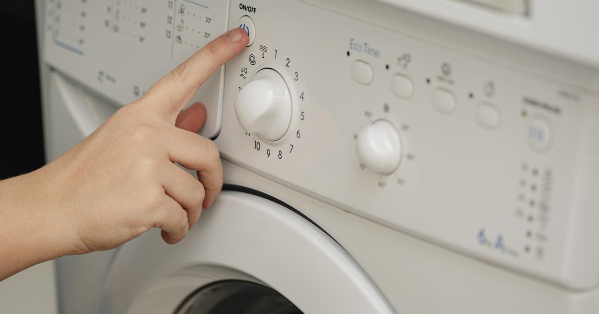 Una persona apretando uno de los botones de la lavadora.