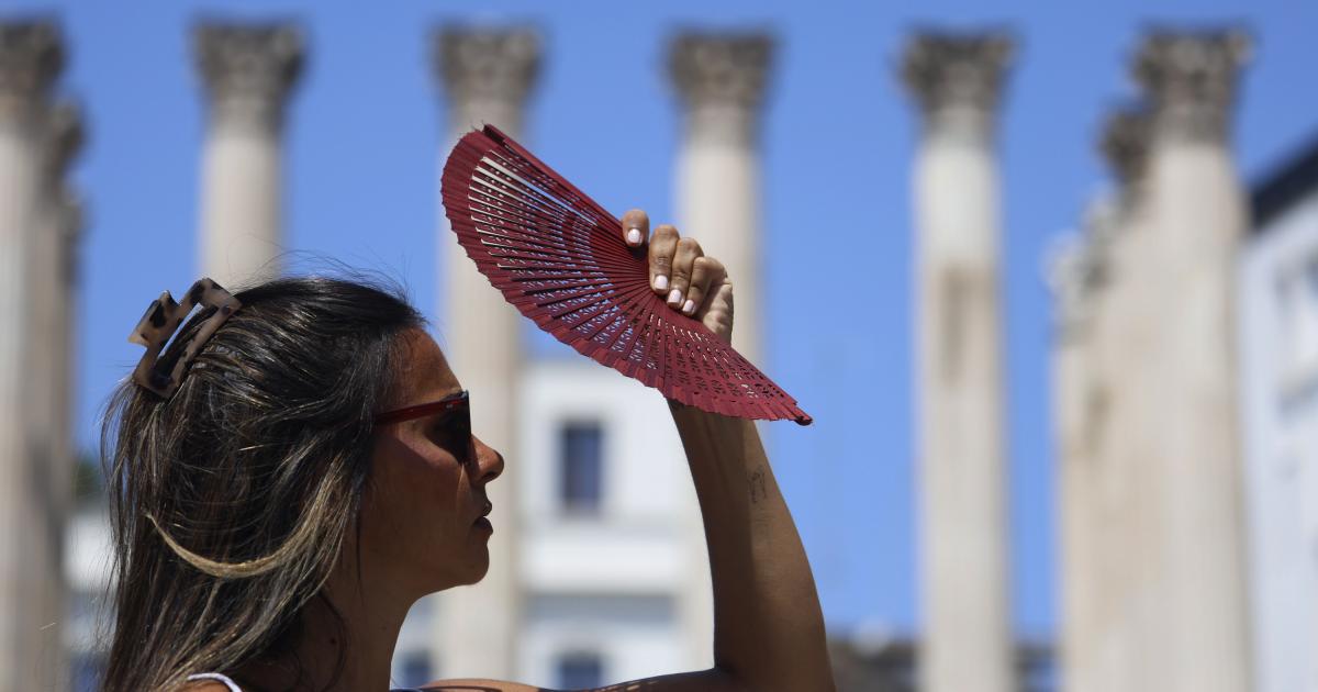 Una joven se tapa la cara con un abanico mientras camina por el centro de Córdoba, en plena ola de calor.