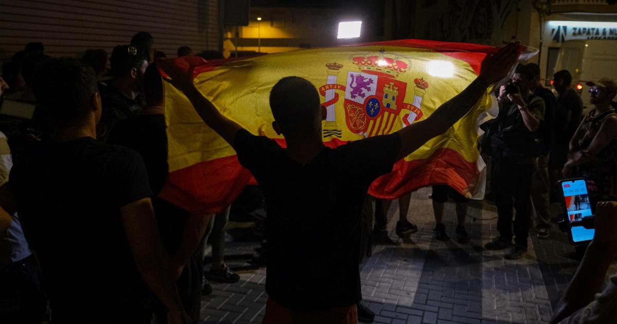 Un manifestante con una bandera de España mientras increpa a periodistas en Torre Pacheco