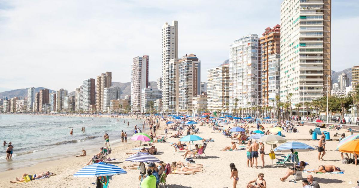 Turistas en la playa de Benidorm durante el verano. Mientras los destinos costeros se llenan, más de un tercio de los españoles no puede permitirse una semana de vacaciones, según el INE.