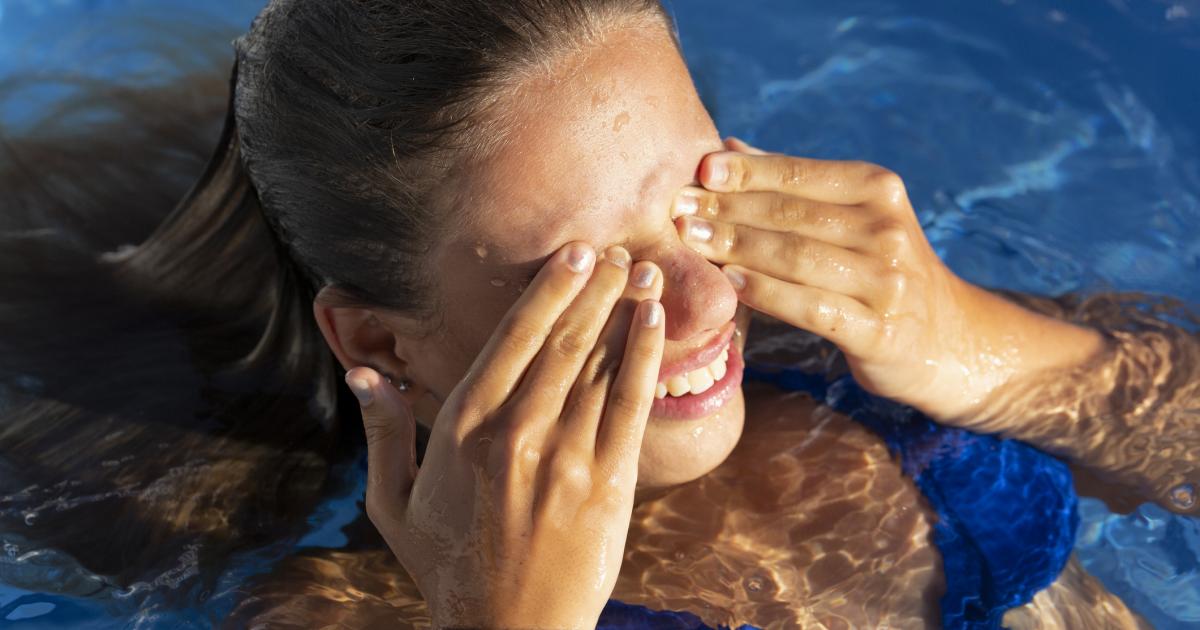 Imagen de archivo de una mujer frotándose los ojos en la piscina.
