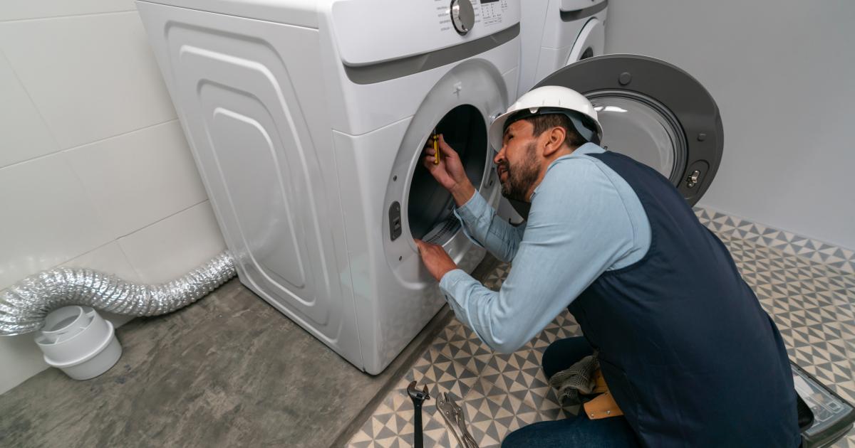 Un técnico reparando o montando una lavadora en una casa.