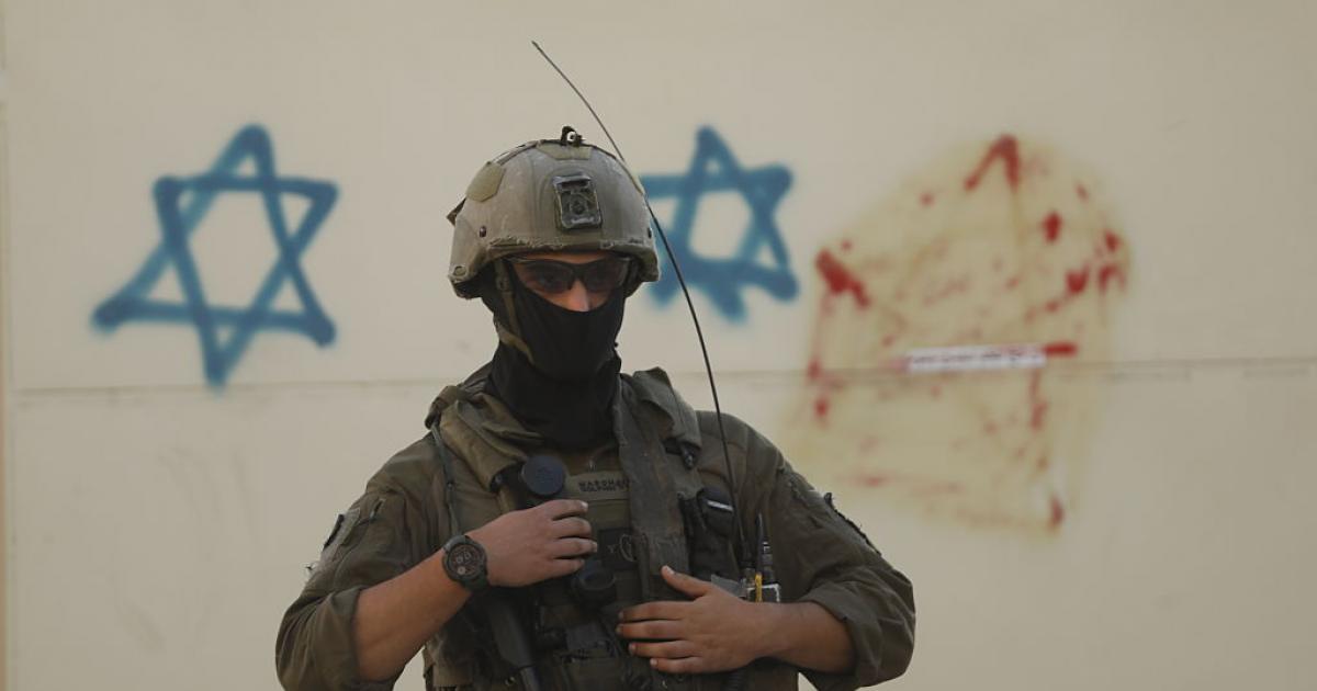 Un soldado de Israel, ante unas pintadas con estrellas de David, en el centro ocupado de Hebrón, en Cisjordania.