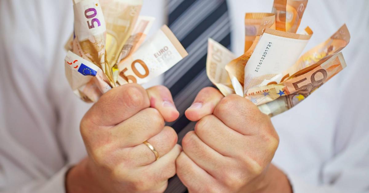 Hombre estrujando el dinero con avaricia y furia