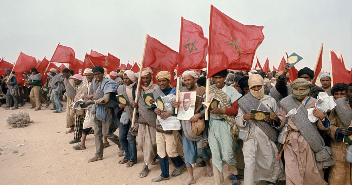 Un grupo de marroquíes con banderas nacionales y retratos del rey Hassan II, avanza hasta el paso del Tah, en la frontera con el Sáhara Occidental, el 6 de noviembre de 1975.