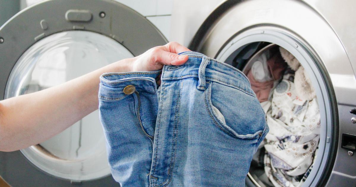 Una persona mete un par de pantalones vaqueros en la lavadora, en una imagen de archivo.