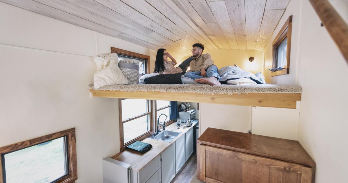 Una pareja, en una cama elevada, en un estrecho minipiso.