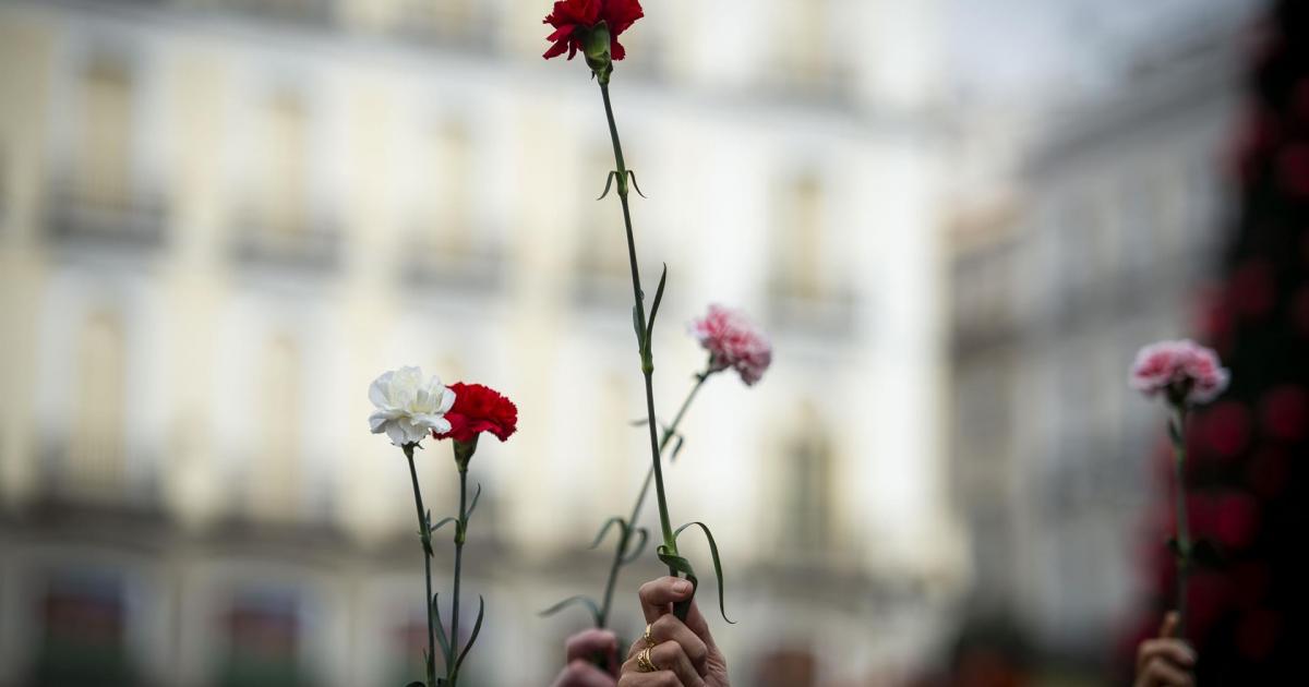 Varias personas sujetan flores durante una manifestación de Marea de Residencias