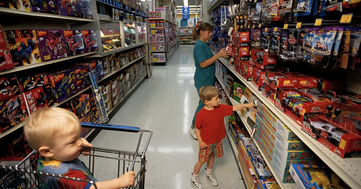 Una mujer y sus dos hijos en el pasillo de los juguetes de una tienda