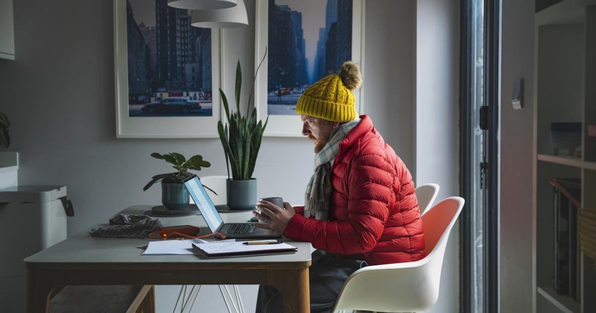 Con el costo de la energía en aumento, un hombre maduro recurre a ropa de invierno para mantenerse abrigado en lugar de encender la calefacción.