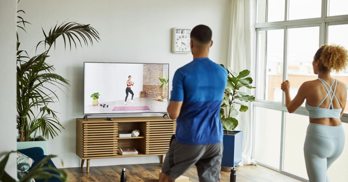 Una pareja haciendo ejercicio frente a una televisión.