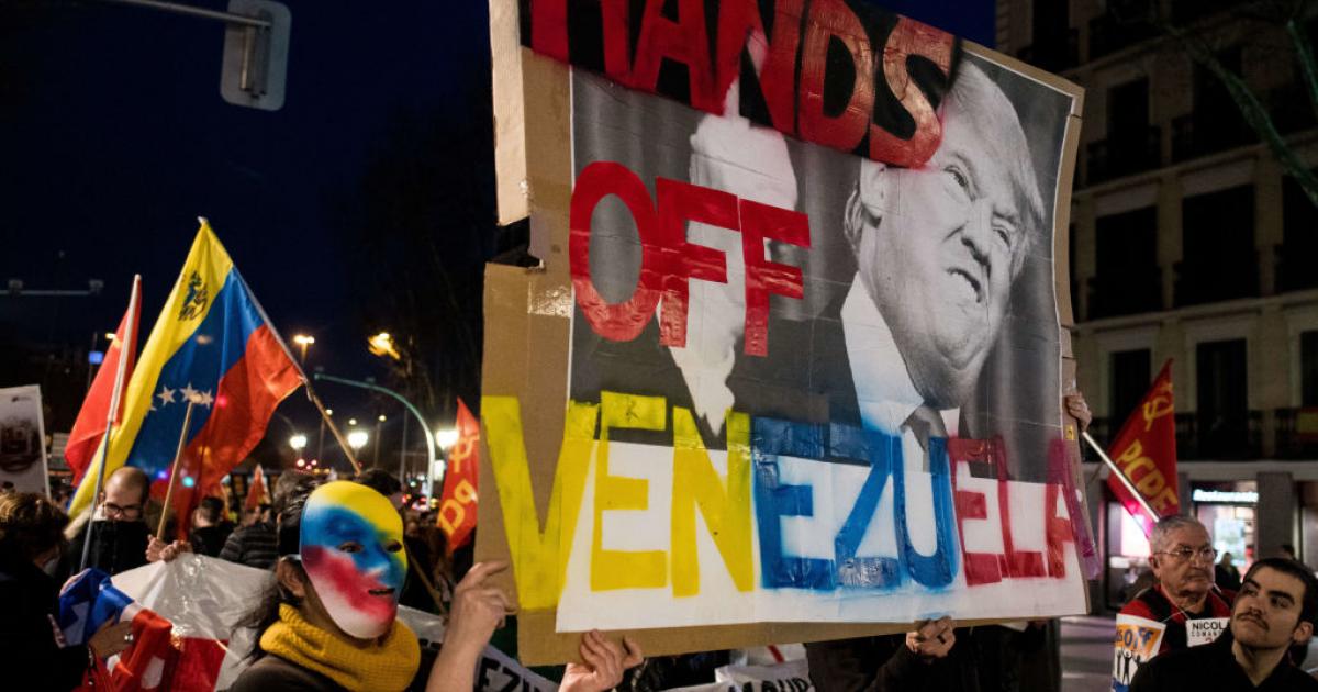 Una manifestante enmascarada porta una pancarta con la imagen del presidente de EEUU, Donald Trump, preclamando que "saque sus manos" de Venezuela, en febrero de 2019.