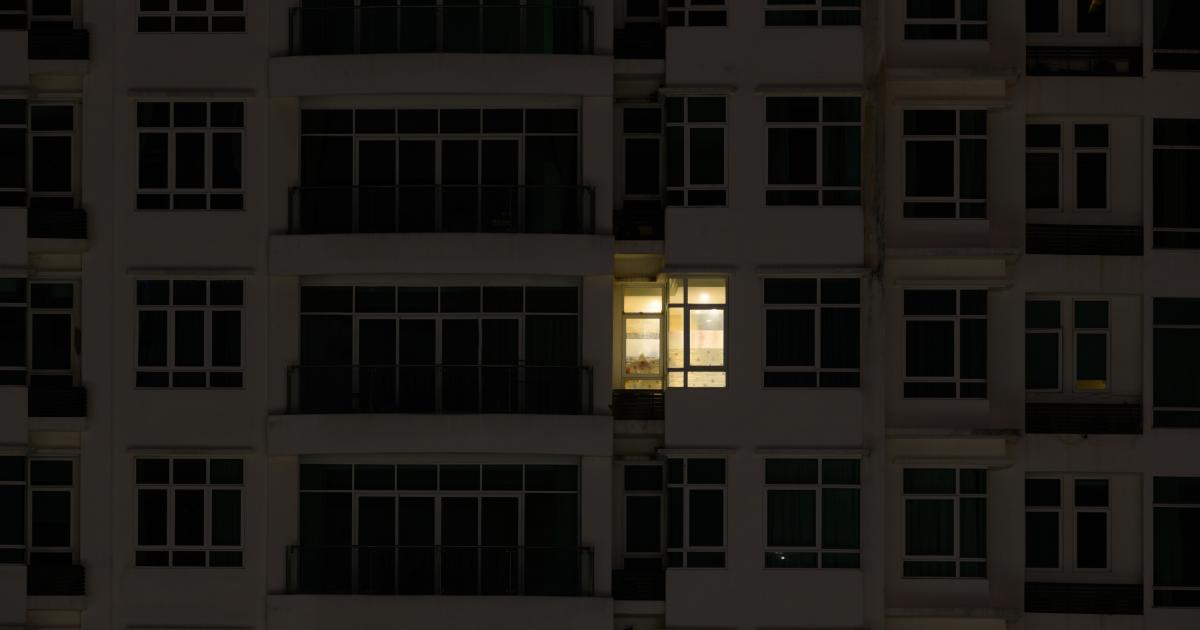 Imagen de archivo de la fachada de un edificio con solo una vivienda con la luz encendida.