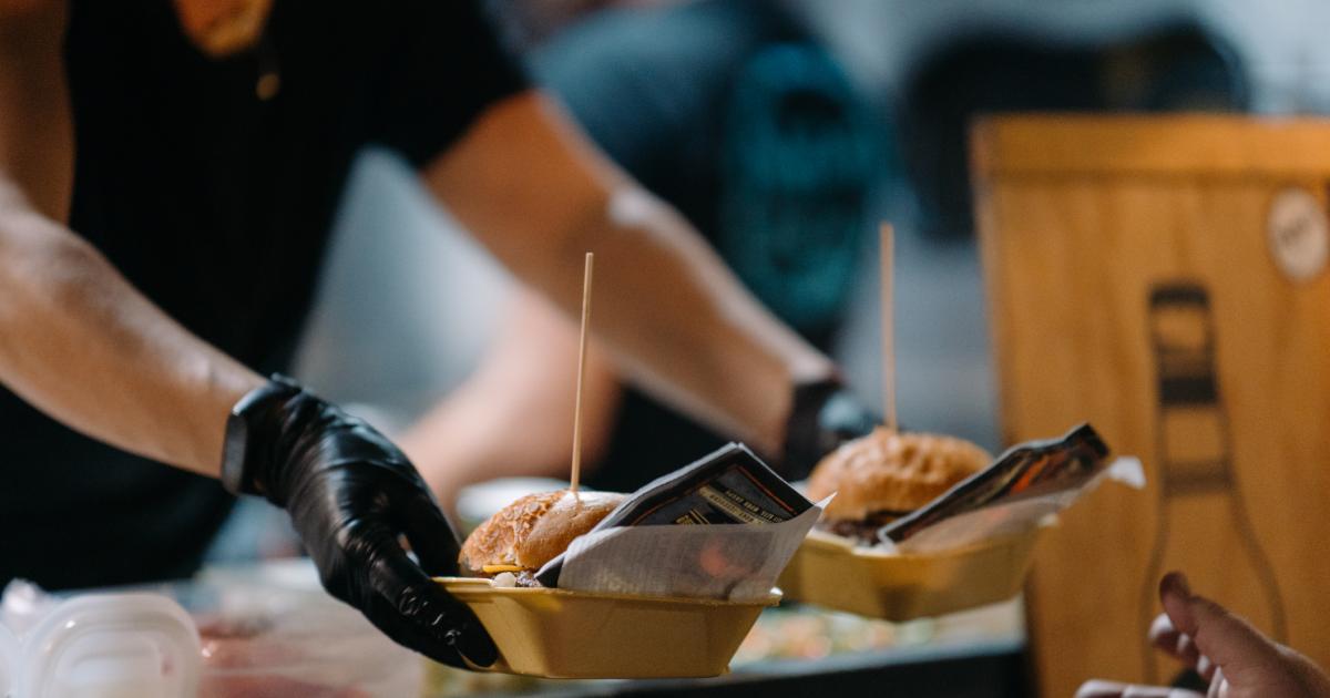Una persona sirviendo hamburguesas en un food truck, en una imagen de archivo