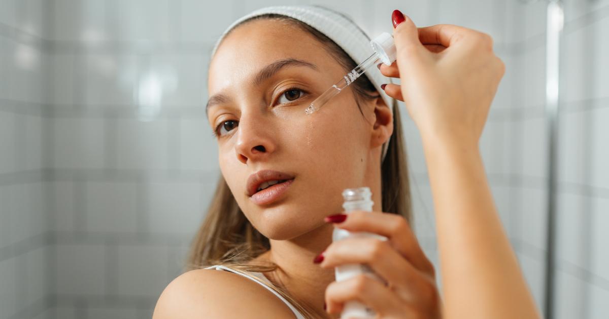 Una mujer aplicándose un sérum en el baño frente al espejo