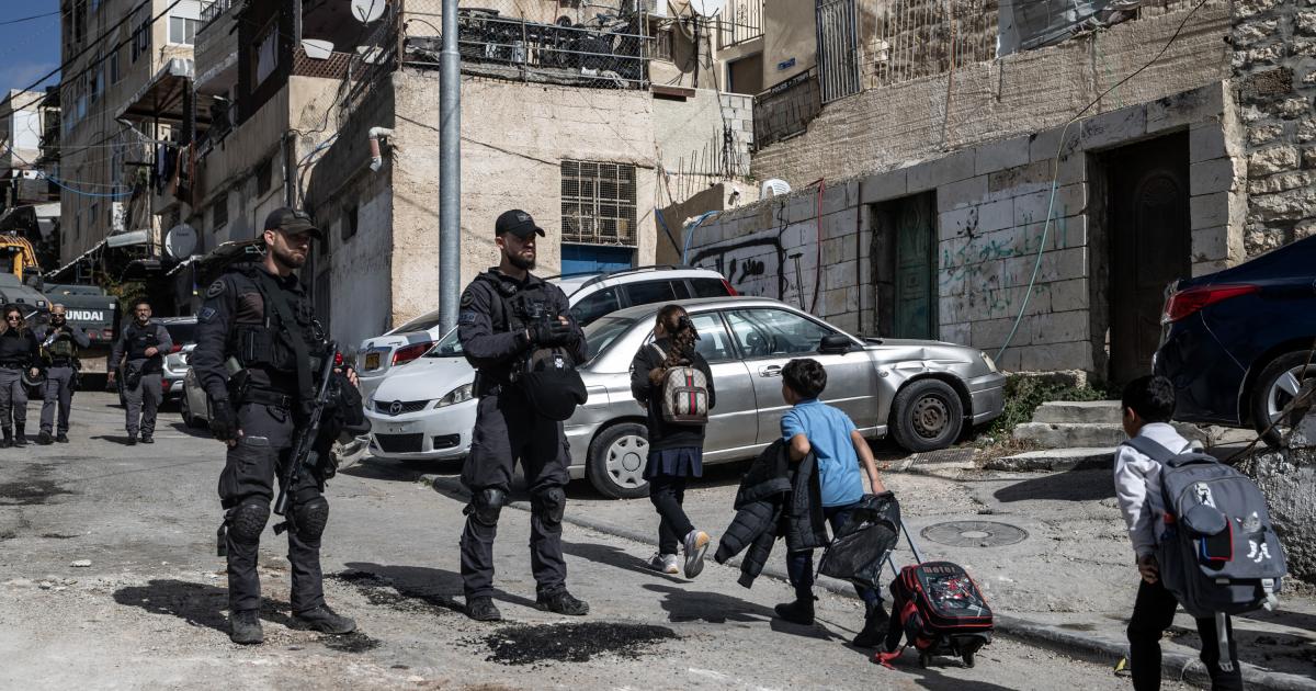 Soldados israelíes vigilan una demolición de una vivienda palestina en el barrio de Silwan, en Jerusalén en la parte de la Cisjordania ocupada, mientras pasan varios escolares palestinos.