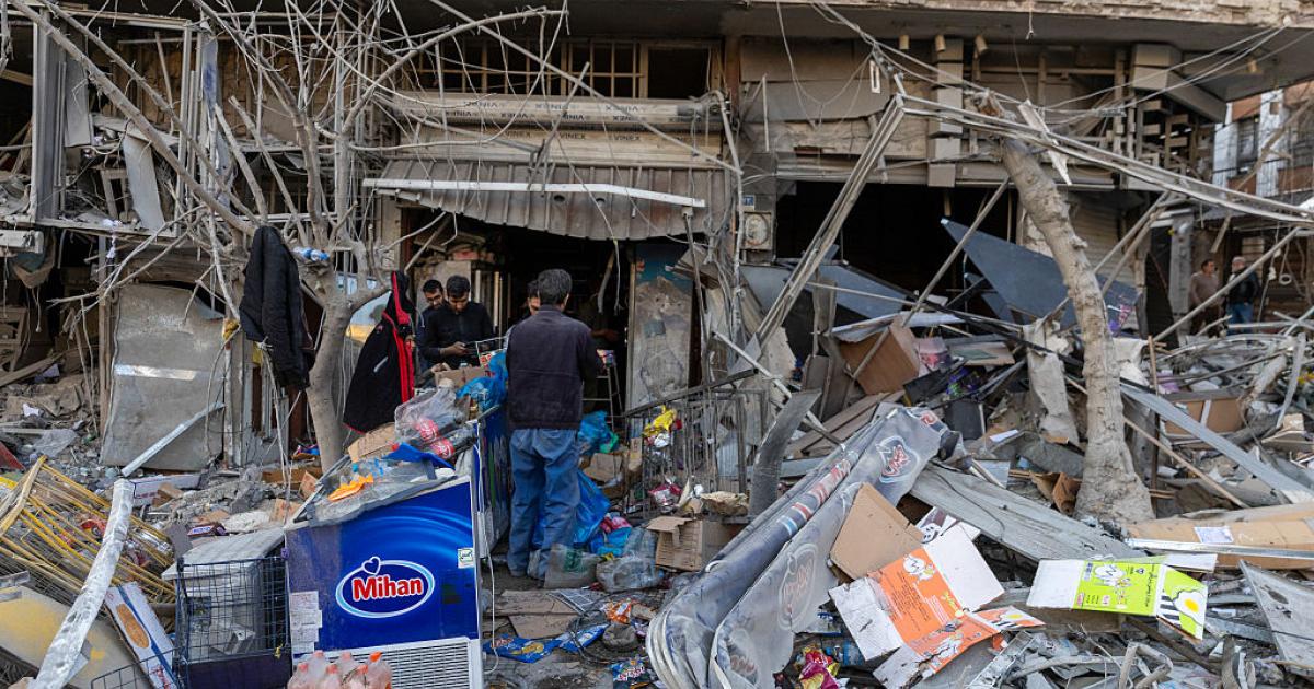 Ciudadanos de Teherán, la capital de Irán, revisan los daños causados en una tienda y una vivienda por los ataques aéreos de EEUU e Israel, 2 de marzo de 2026.