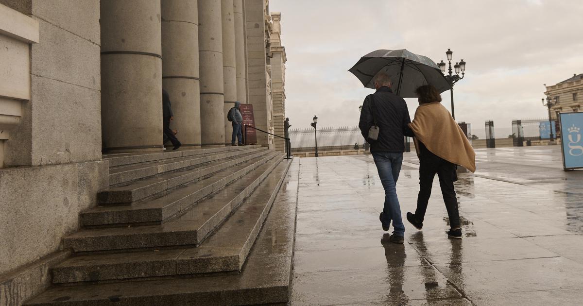 Imagen de archivo de dos personas caminando con un paraguas en Madrid.