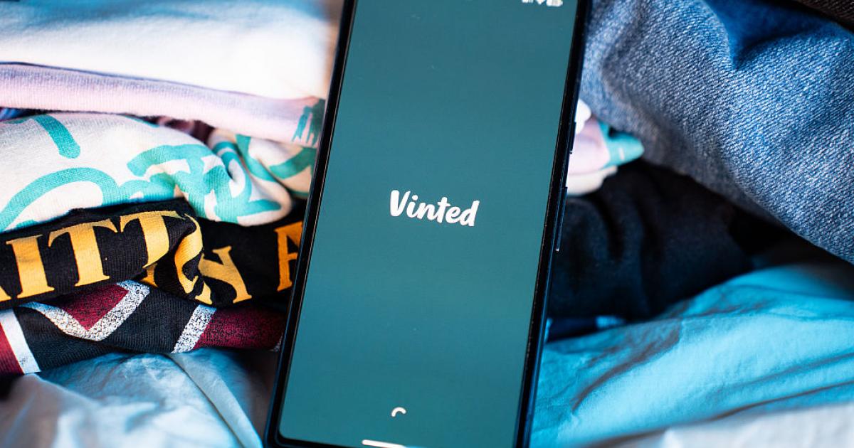 Imagen un móvil con el logo de Vinted junto a varias prendas de ropa