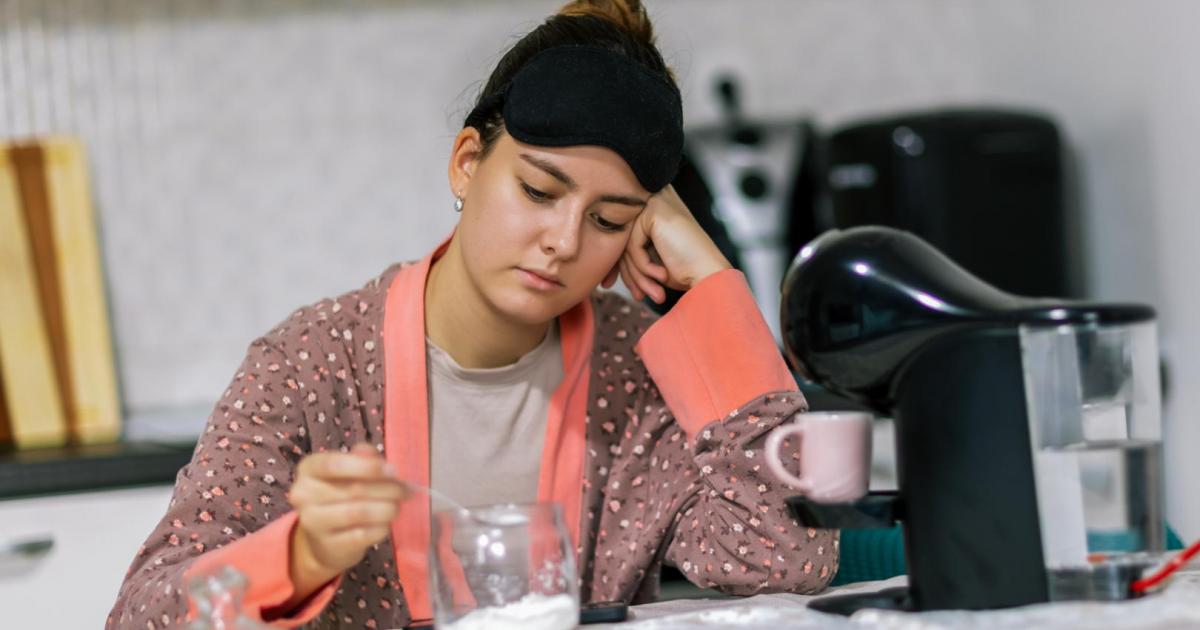 Una joven añade azúcar a su café en casa, preparando su bebida matutina con cuidado