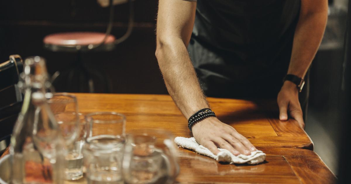 Un camarero limpia la mesa de un bar.