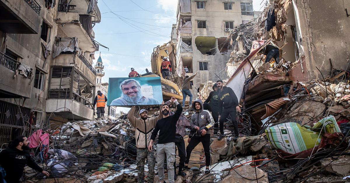 Partidarios de Hezbolá muestran una fotografía del asesinado líder Hassan Nasrallah en Hey al-Soulom, en los suburbios del sur de Beirut, el 12 de abril de 2026, entre ruinas de ataques de Israel.