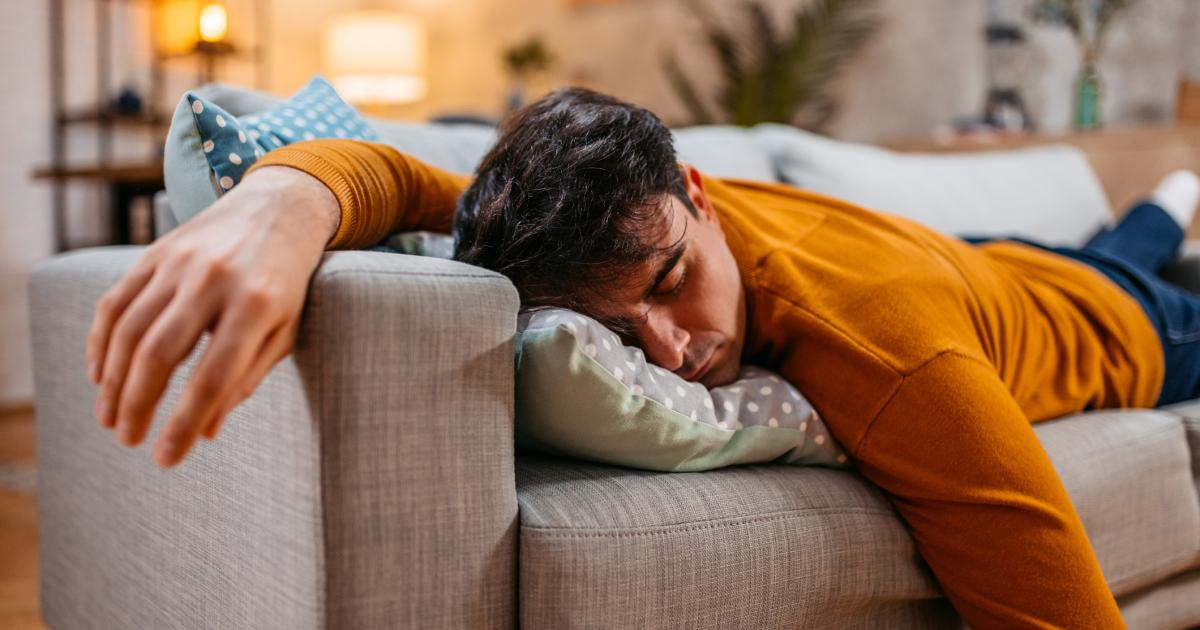 Un joven cansado se queda dormido en el sofá del salón.