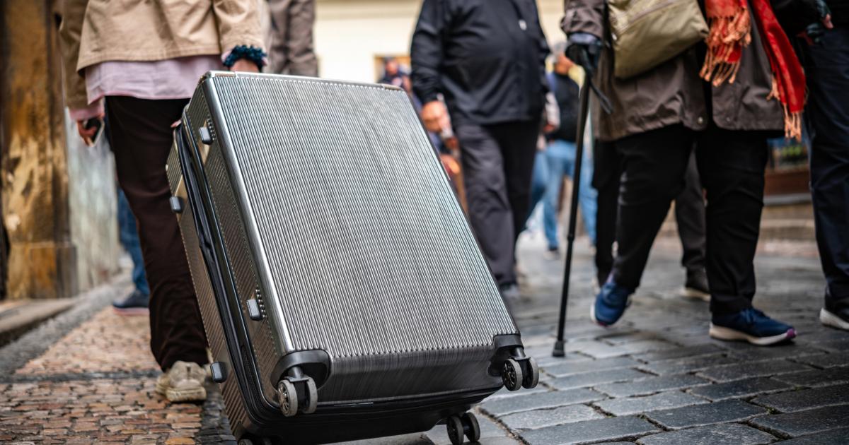 Un turista, paseando con una maleta por la calle de una ciudad.