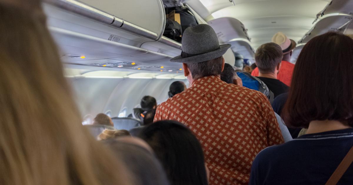 Varias personas, de pie para salir del avión.