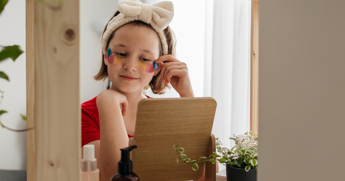Una adolescente cuida delicadamente su piel, colocando parches calmantes debajo de los ojos