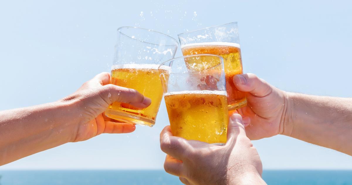 Varias personas beben cerveza en una playa.