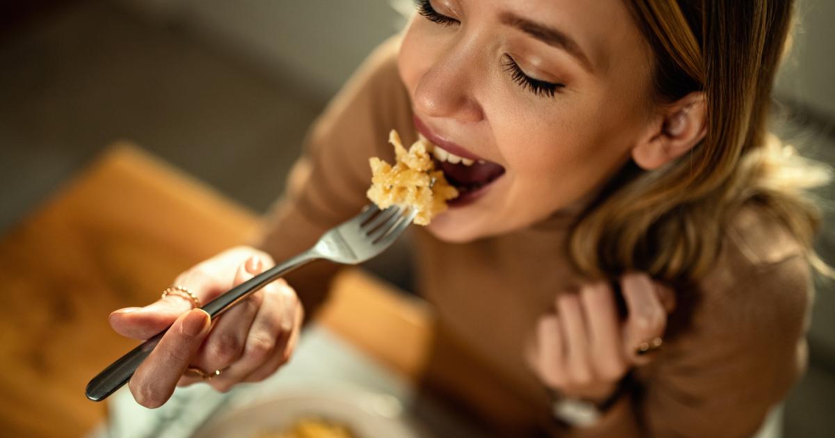 Primer plano de una mujer feliz cenando pasta.