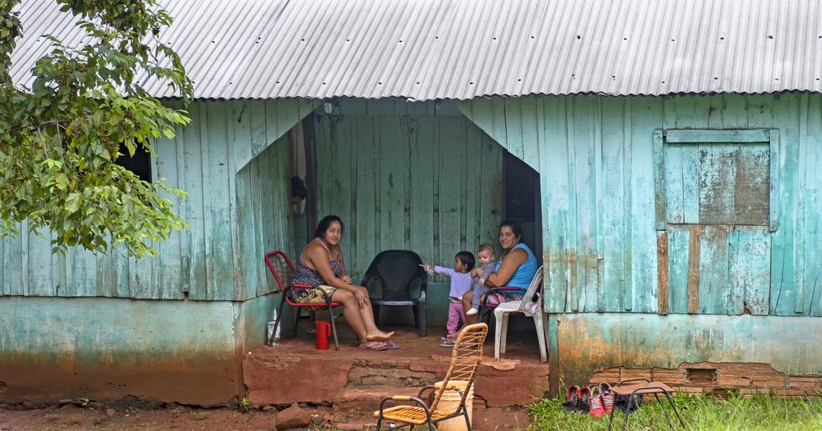 Familia posando junto a una cabaña de madera con techo de chapa ondulada en una aldea rural cerca de Ciudad del Este, Alto Paran‡, Paraguay.