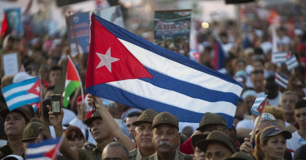 Miles de cubanos enarbolan su bandera nacional, entre militares del ejército revolucionario, en la marcha del Primero de Mayo de 2024, en La Habana.