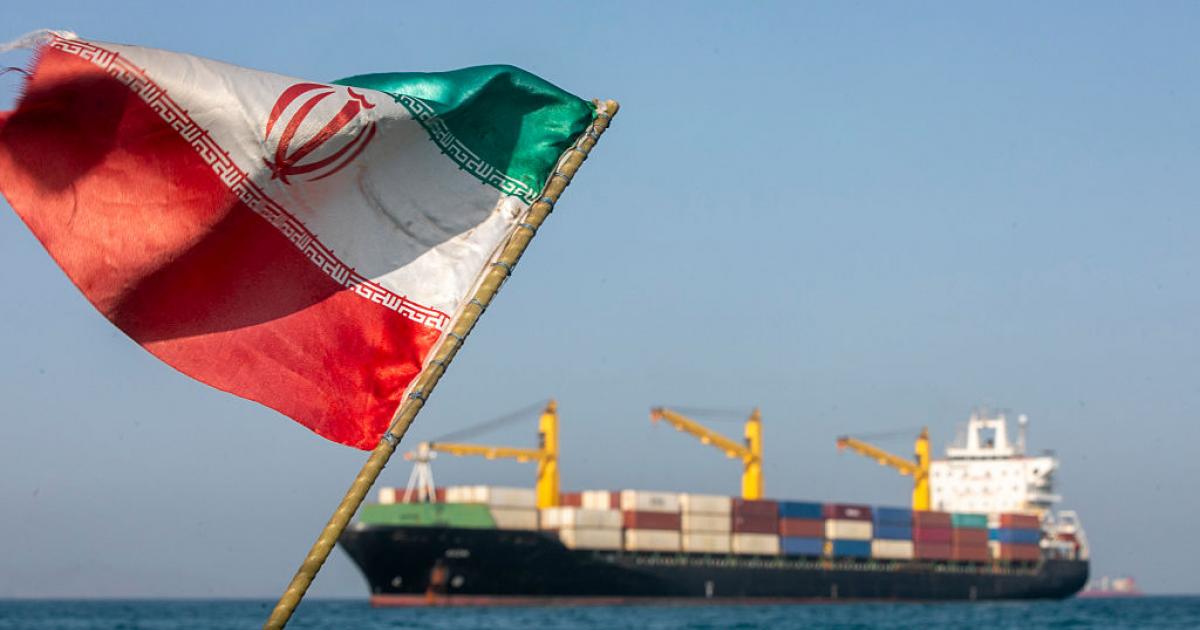 Una bandera iraní ondea al viento mientras varios barcos permanecen anclados, el 16 de mayo de 2026, en el estrecho de Ormuz, cerca de la isla de Larak.