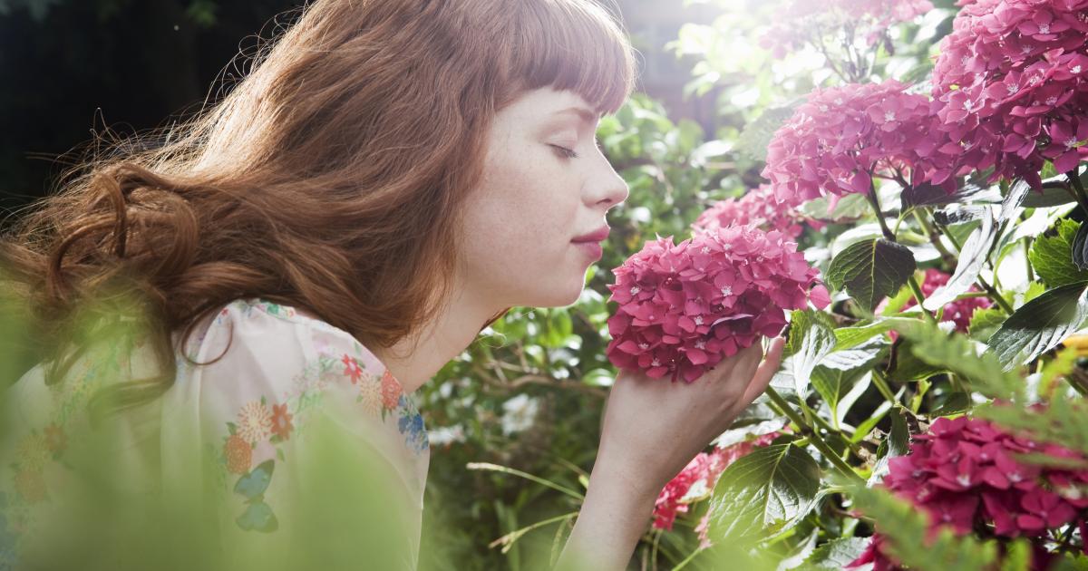 Una mujer huele una flor