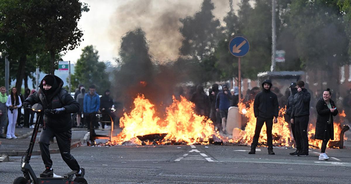 Un grupo de jóvenes se congrega frente a una barricada en llamas en Duncairn Gardens, el 9 de junio de 2026, en Belfast (Irlanda del Norte), en mitad de una ola de ataques racistas.
