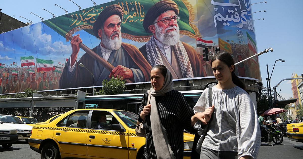 Unas mujeres pasan ante un cartel con los rostros de Ruhollah Jomeini y Ali Jamenei, los antiguos líderes supremos de Irán, el 8 de junio de 2026, en Teherán.